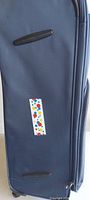 Side view of navy blue suitcase showing fabric, side handle, wheels