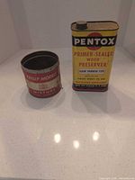 Philip Morris tobacco tin and Pentox wood preserver can side by side on countertop