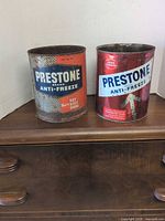 Front view of both vintage Prestone Anti-Freeze tins showing graphics, colours and wear