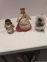 Front view of three wooden dolls on counter