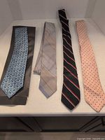 Four neckties laid out side by side showing overall colors and patterns