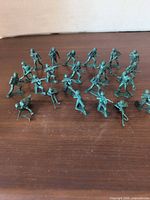Full set of 22 green plastic toy soldiers spread out on surface