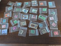 Array of thirty postage stamps each in its own clear sleeve laid out on dark surface