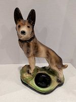 Front view of glazed ceramic German Shepherd figurine on base with dish