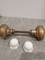 Brass door knob set and two white caps displayed on fabric surface