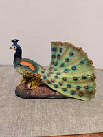 Full view of painted ceramic peacock on base