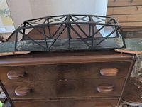 Full view of black metal truss bridge on dresser