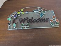 Front view of stained glass welcome sign on wooden surface