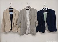 Front view of three blazers: beige, light grey, navy