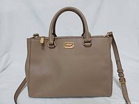 Front view of taupe Michael Kors Kellen satchel with top handles and crossbody strap attached