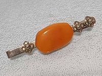 Top view of money clip showing amber cabochon and floral accents
