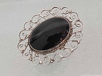 Front view showing black onyx cabochon and silver filigree frame