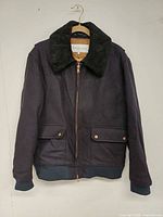 Front view of navy wool bomber jacket with detachable shearling collar and copper zip