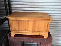 Closed chest showing front and top surfaces with natural wood finish and some wear.