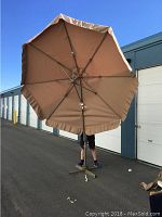 Large beige patio umbrella fully opened outdoors, approximately 9 feet tall and wide.