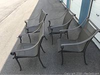 Four dark gray aluminum patio chairs with mesh seats and backs, curved armrests, legs, and some paint chips visible.