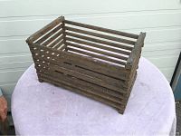 Wooden slatted crate placed on a cloth-covered surface showing overall condition and structure.