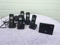 Five Gigaset cordless handsets with charging bases arranged on a table along with the Gigaset A580 IP base station.