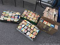 Six boxes filled with eight-track cartridges arranged outdoors on asphalt surface