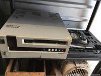 Front view showing cassette slot, control buttons and surface marks on silver metal casing.