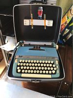 Full view of the Smith Corona Super Sterling typewriter in its open hard case with key attached inside the lid.