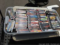 Large plastic bin filled with stacked PS2 game cases