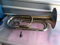 Full view of silver-tone bugle with visible wear and loose mouthpiece placed beside it.