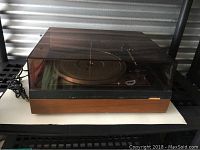Full view of Dual 1216 turntable with closed dust cover. Shows wood grain base and black top.