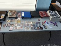 Full tabletop view showing binders, loose cards, magazines, small box, white storage box, medals and tickets