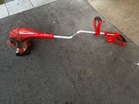 Full view of Black & Decker GrassHog corded string trimmer lying on ground