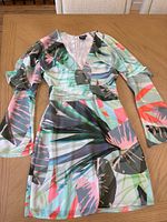 Front view of Marciano tropical leaf print dress laid flat showing design, neckline and sleeves