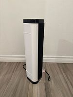 Side view of white and black tower heater with power cord