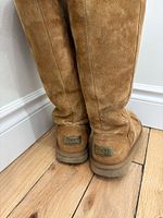Full view of both tall chestnut UGG boots standing upright.