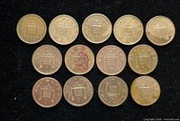 Obverse sides of thirteen British one penny coins laid out on black background