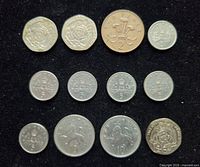 Obverse designs showing reverse details of 12 British coins on black surface