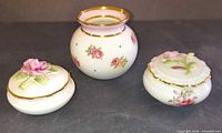 Front view of three bone china pieces displaying shapes, floral designs and gilding