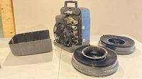 Projector standing with case cover removed and two reel trays visible