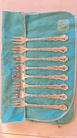 Eight ornate silver-plated forks laid on turquoise Birks felt pouch