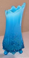 Full view of blue opalescent vase showing ruffled top and feet