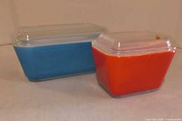 Blue and red-orange Pyrex refrigerator dishes with lids, side view