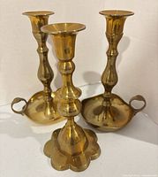 Front view of all three brass candlesticks showing overall form and finish