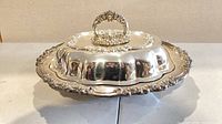 Full view of covered serving dish showing ornate rim and handle