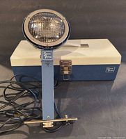 Smith-Victor L8 photo light head on stand with cord, carrying case behind