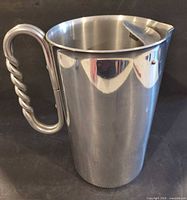 Front view of stainless steel pitcher showing twisted handle and hinged lid