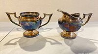 front view of sugar bowl and creamer showing form and patina