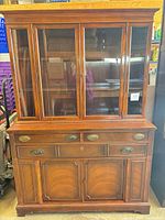 Front view showing glass upper doors, drawers, lower cabinet doors, veneers and hardware