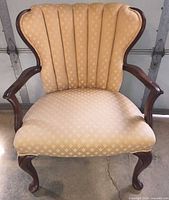 Front view of Queen Anne armchair showing fabric pattern, channel back, wood arms and cabriole legs