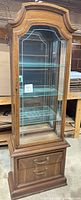 Front view of curio cabinet showing glass door, shelves, drawers