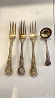 Front view of three dinner forks and ladle showing pattern and finish