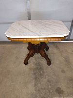 Full view of table showing marble top and carved base